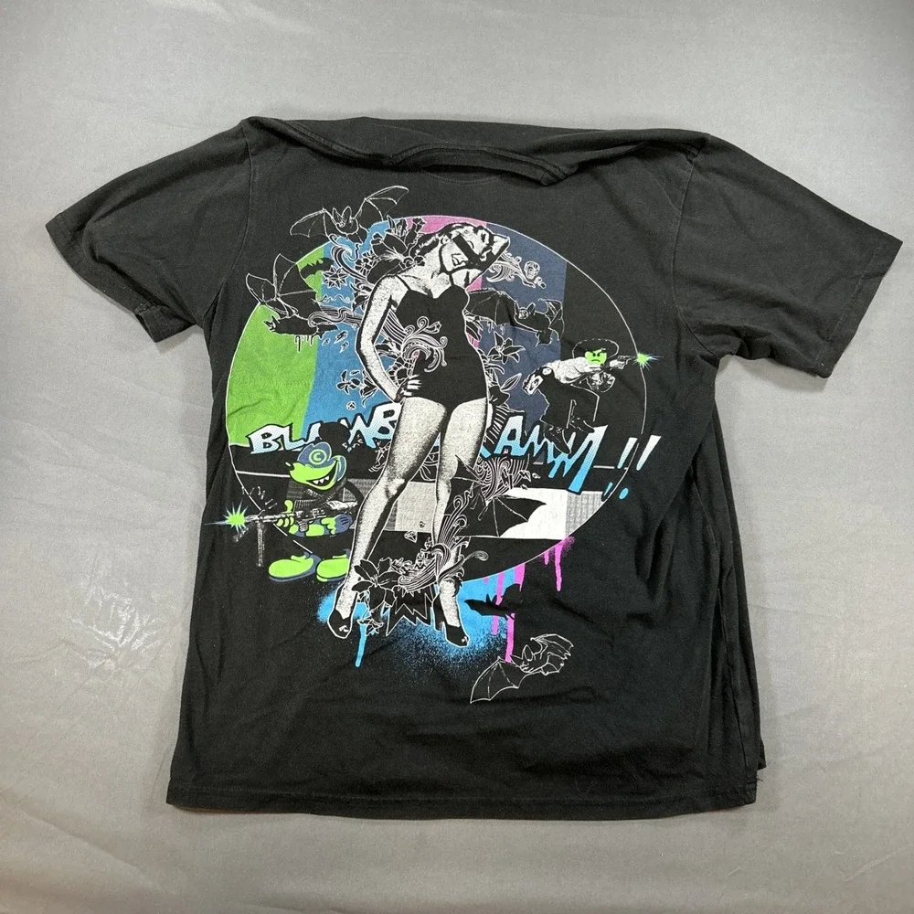 black graphic T-shirt features a central illustration of a woman in a black Sz L